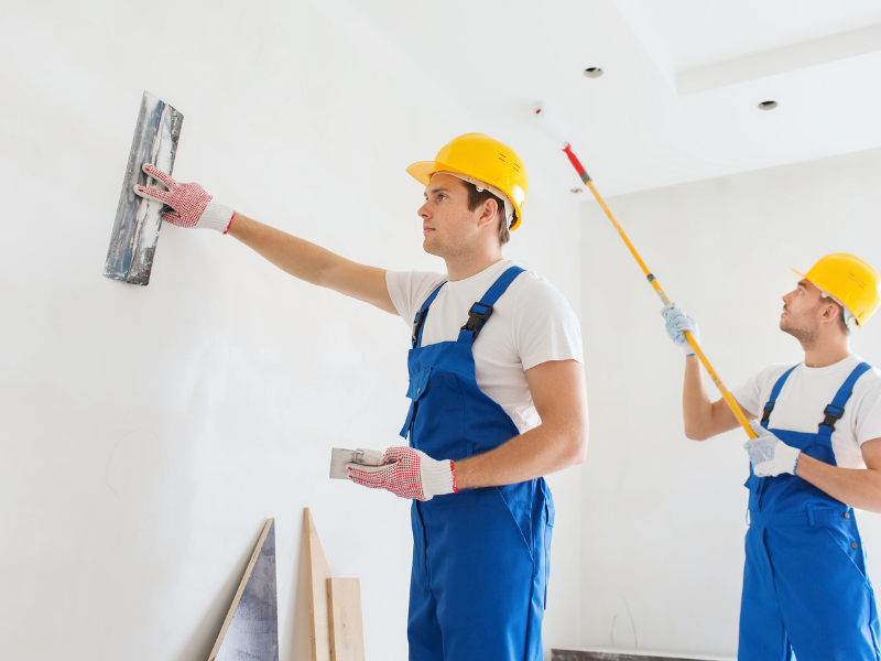 Two professional painters applying wall paint indoors