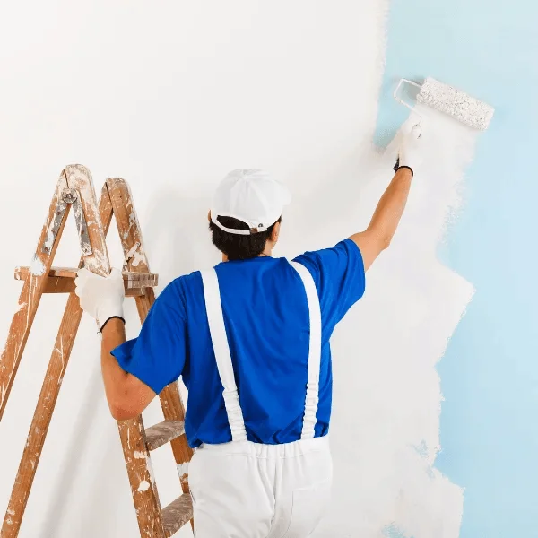 Painter applying wall paint with roller indoors near ladder